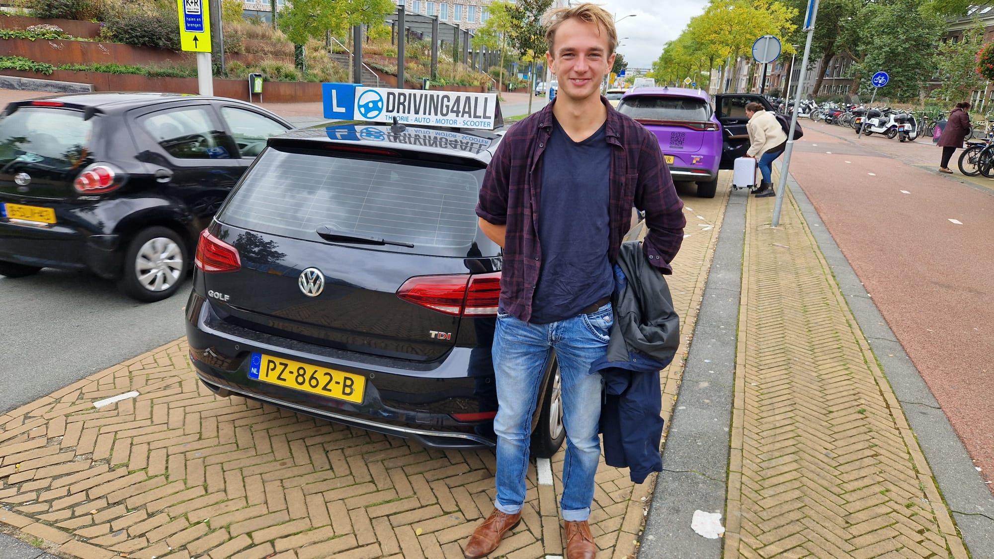 Geslaagde leerling naast de lesauto van Driving4all in Delft