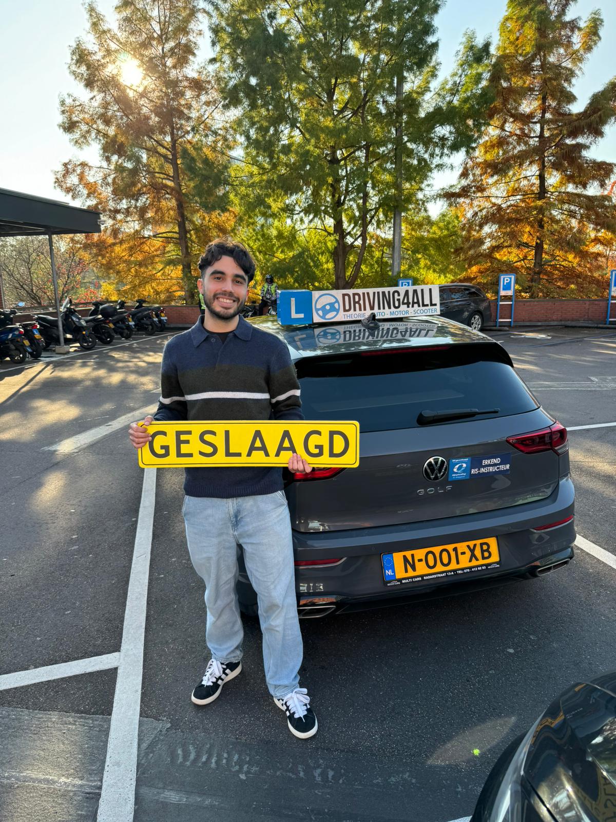 Geslaagde leerling van Driving4all met geslaagd-bord bij de lesauto